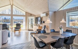 A spacious living area with a wooden ceiling, large windows, a dining table with chairs, and a TV mounted on the wall. - Cozy home in Ansager with sauna (Ansager)