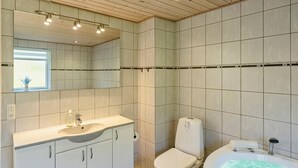 A modern bathroom with a vanity, toilet, and bathtub. - Cozy home in Ansager with sauna (Ansager)