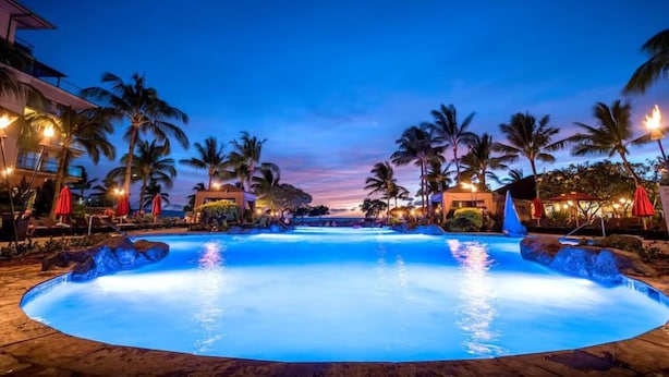 Una gran piscina al aire libre rodeada de palmeras y edificios de hotel.