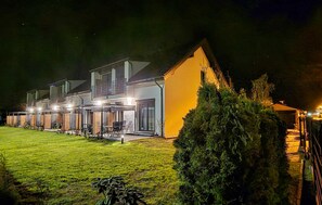 Een modern, twee verdiepingen hoog gebouw met een goed verlichte ingang en een overdekt terras.