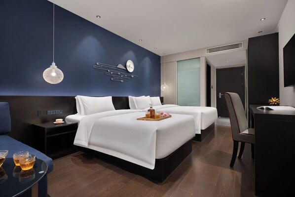 Une chambre d’hôtel moderne avec deux lits, un bureau et un coin salon.