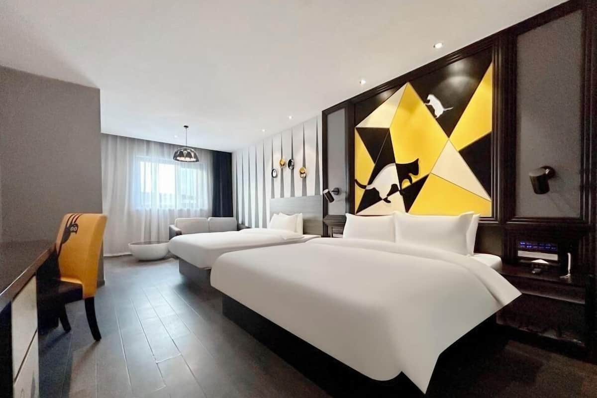 Une chambre d’hôtel moderne dotée d’un grand lit, d’un canapé, d’un coin repas et d’un mur décoratif.