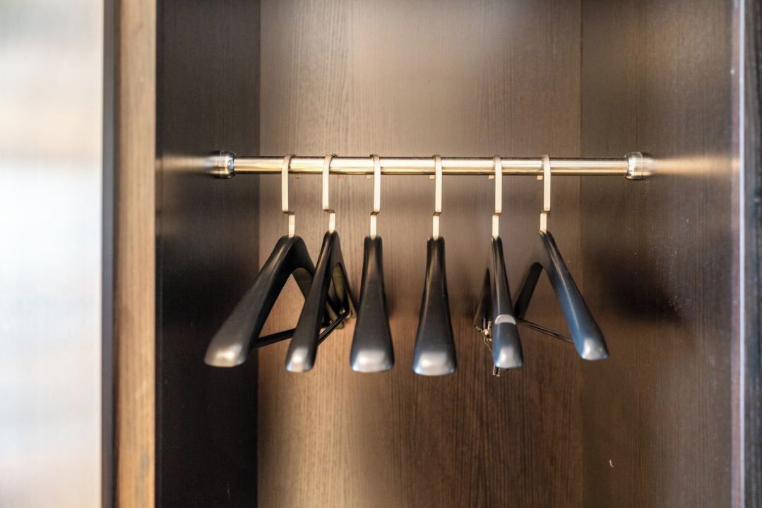 Un perchero metálico con varios ganchos negros, probablemente para colgar objetos, en una habitación con paneles de madera.