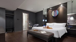 Ein modernes Hotelzimmer mit einem großen Bett, einem Nachttisch, einem Spiegel und einem Kleiderschrank.