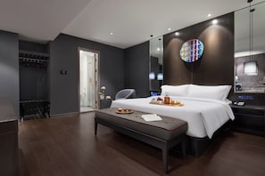 Ein modernes Hotelzimmer mit einem großen Bett, einem Nachttisch, einem Spiegel und einem Kleiderschrank.