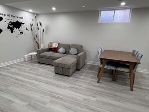 En moderne stue med en grå sofa, et træspisebord og et verdenskort på væggen.