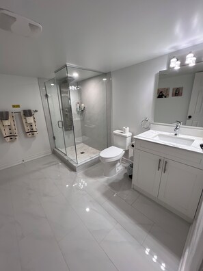 Une salle de bain moderne avec une douche à parois de verre, des toilettes, un lavabo avec un miroir et un meuble de rangement.