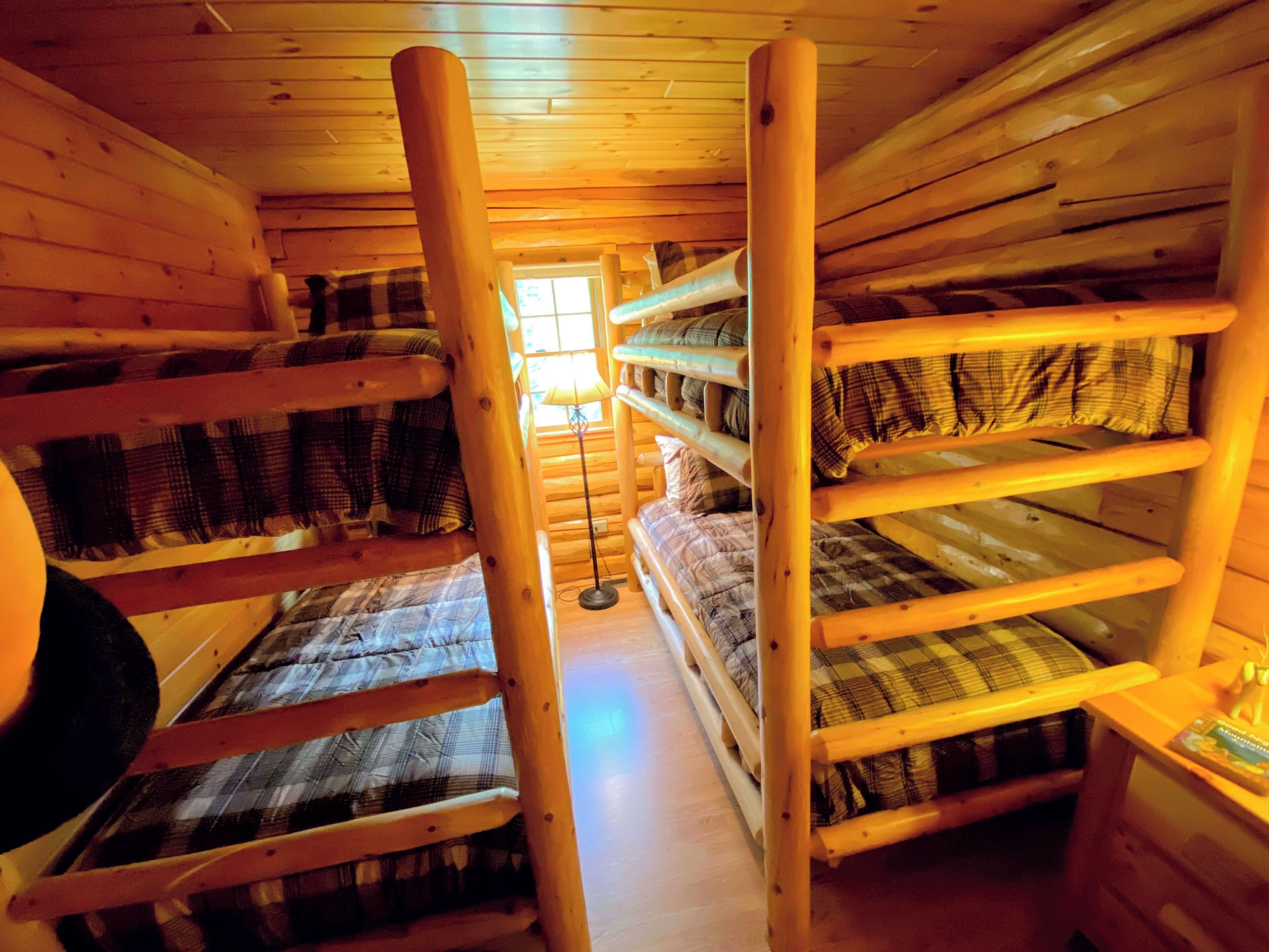A cabin with bunk beds, a wooden interior, and a window allowing natural light.