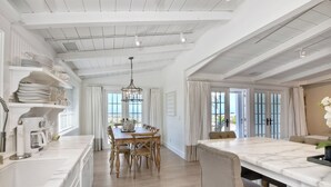 Una cocina amplia con armarios blancos, una mesa de comedor de madera y una isla de mármol.