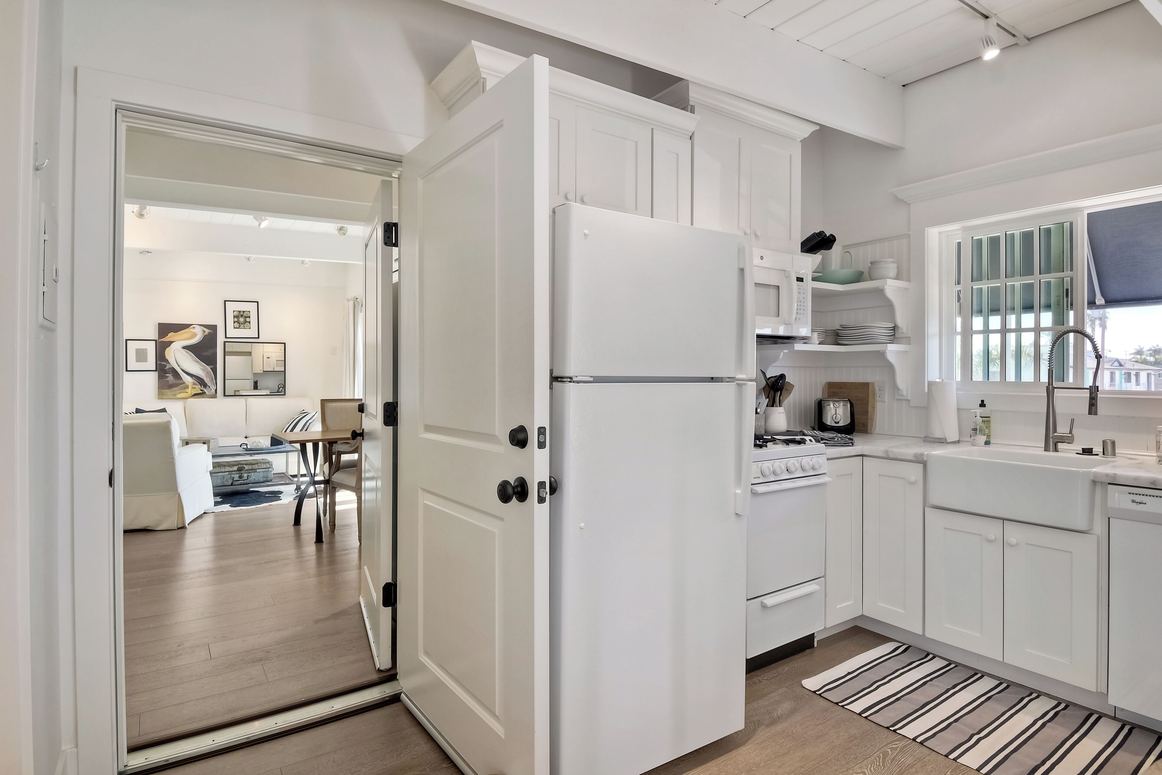 A modern kitchen with white cabinetry, a refrigerator, stove, and sink.