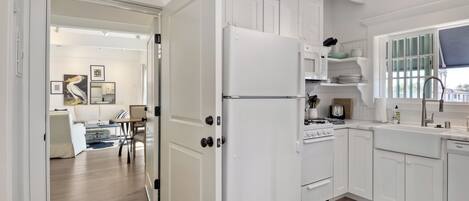 A modern kitchen with white cabinetry, a refrigerator, stove, and sink.