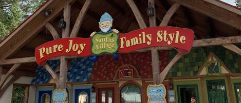 A building with a sign reading 'Pure Joy Family Style' and 'Santa's Village.' There are two doors labeled 'ADMISSION,' one blue and one red.