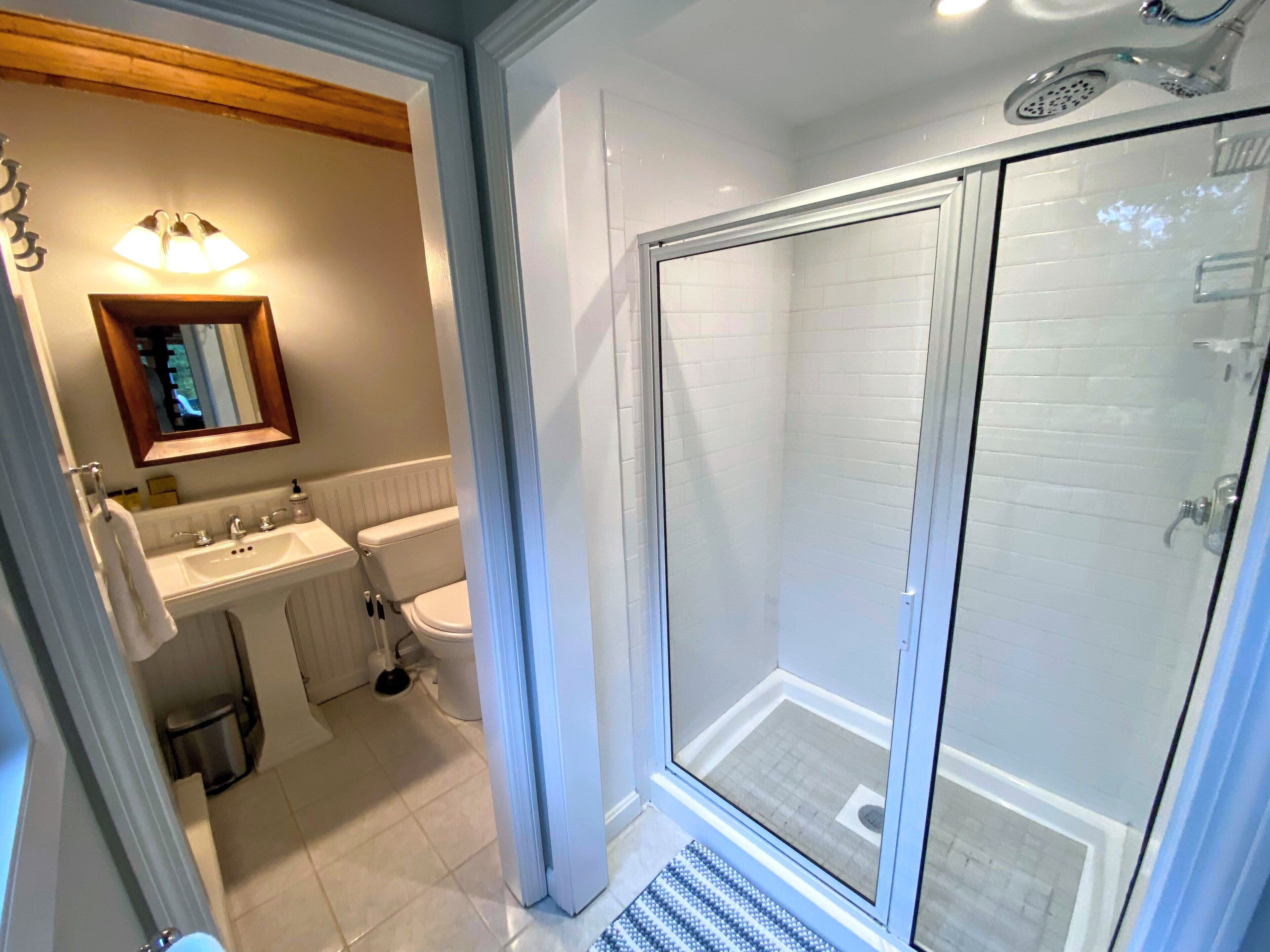 Une salle de bain équipée d’une douche, de toilettes, d’un lavabo et d’un miroir.
