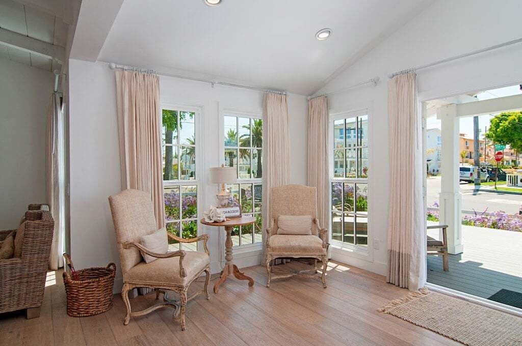 A spacious room with large windows, wicker furniture, and a view of the street.