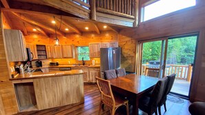 A wooden cabin with a kitchen, dining area, and large windows. - 1800or Unique 'yurt' Home in Bretton Woods 1 mi to Skiing, Firepit, Foosball, Beach! Hot tub (Bretton Woods)