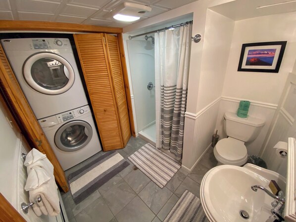 A compact bathroom with a washing machine, toilet, and sink.