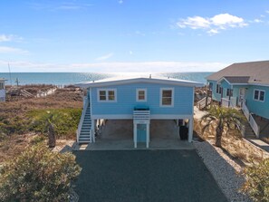 Ein zweistöckiges Haus mit einer Veranda und Blick auf das Meer.