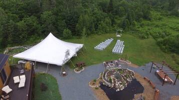 Montaje para una boda al aire libre con una carpa, asientos y un área de jardín decorativa.