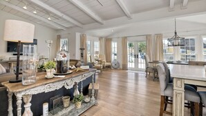 A spacious living area with a wooden floor, a large dining table, and a seating arrangement including a sofa and chairs. - 180 n 190 Walnut Entire Home (Carlsbad)
