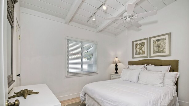 A bedroom with a bed, a nightstand, a lamp, a ceiling fan, and two framed pictures on the wall. - 180 n 190 Walnut Entire Home (Carlsbad)