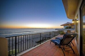 A balcony with a view of the ocean at sunset, featuring a railing, a chair, and a small table. - 2751 Ocean Street (Carlsbad)