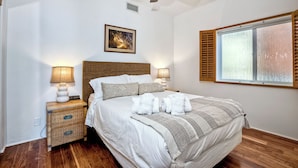 A neatly made bed with white linens and a gray throw blanket, a wooden headboard, two bedside lamps, a wicker nightstand, and a ceiling fan. - 2751 Ocean Street (Carlsbad)