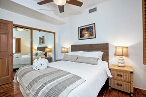 A neatly made bed with a striped blanket, a bedside lamp, and a wicker nightstand. - 2751 Ocean Street (Carlsbad)