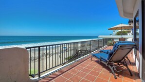 A balcony with a view of the beach and ocean, two sun loungers, and a patio umbrella. - 2751 Ocean Street (Carlsbad)