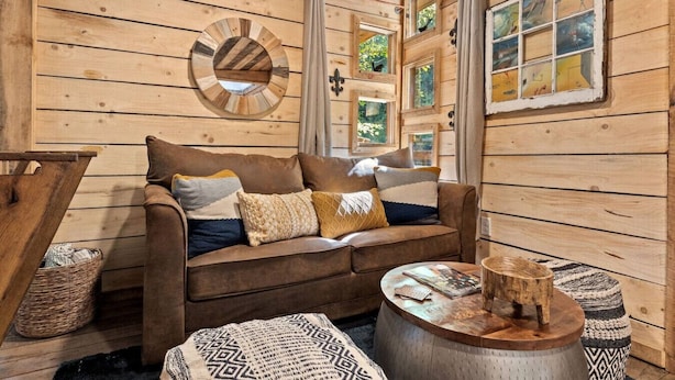 A cozy cabin interior with a brown leather sofa, a round wooden coffee table, and a woven basket. - Amazonia (Rogers)