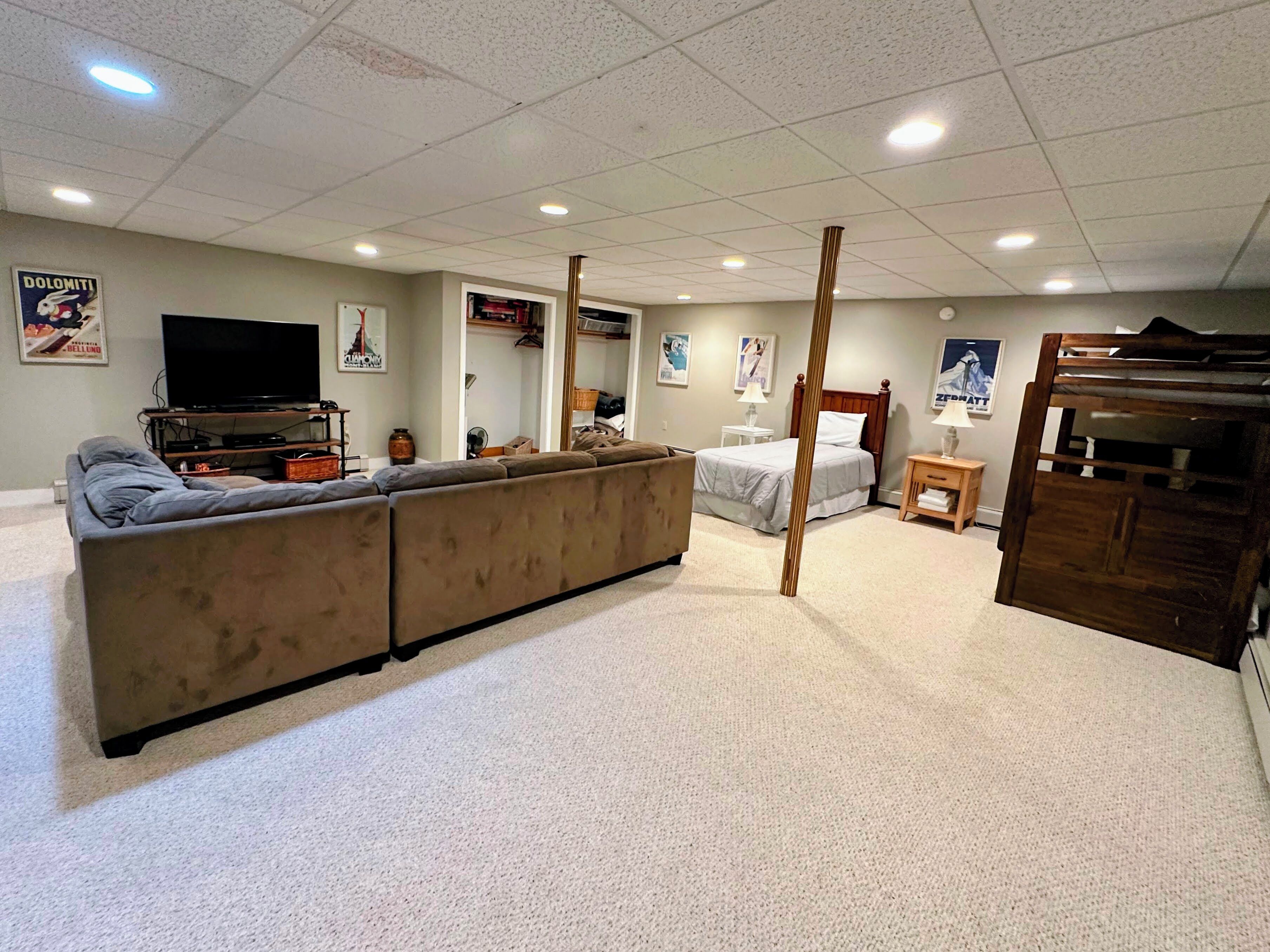 A living room with a large sofa, a bed, a TV, and a wooden structure.