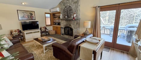 A cozy living room with a fireplace, a television, and a stone accent wall.