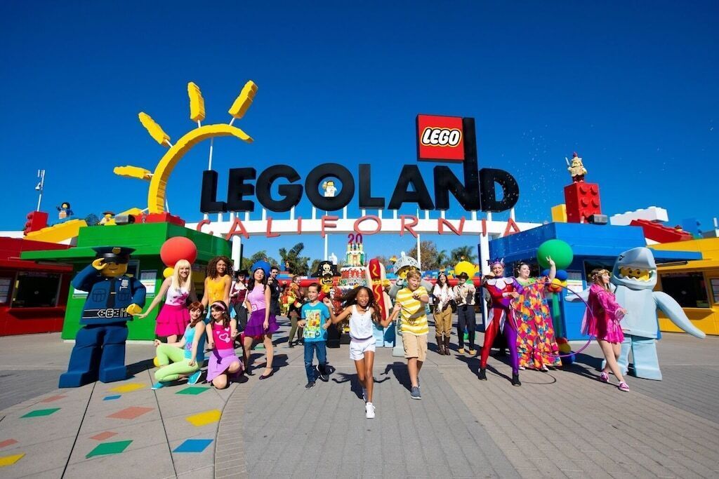 A group of people posing in front of a LEGO-themed entrance with a sign reading "LEGOLAND California".