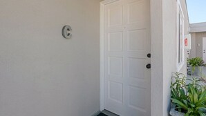 A white door with a small circular sign above it, a white wall, and a small step leading to the door. - 3690 Carlsbad Boulevard - Unit C (Carlsbad)