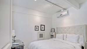 A bedroom with a large bed, white walls, and a ceiling fan. - 3690 Carlsbad Boulevard - Unit D (Carlsbad)
