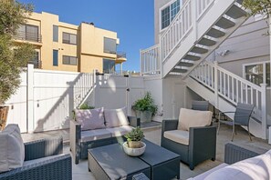 A modern outdoor patio with wicker furniture, a staircase, and a building in the background.