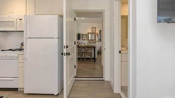 A kitchen with white cabinets, a refrigerator, and a stove. - 3690 Carlsbad Boulevard - Unit D (Carlsbad)