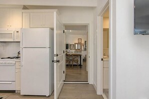 A kitchen with white cabinets, a refrigerator, and a stove. - 3690 Carlsbad Boulevard - Unit D (Carlsbad)