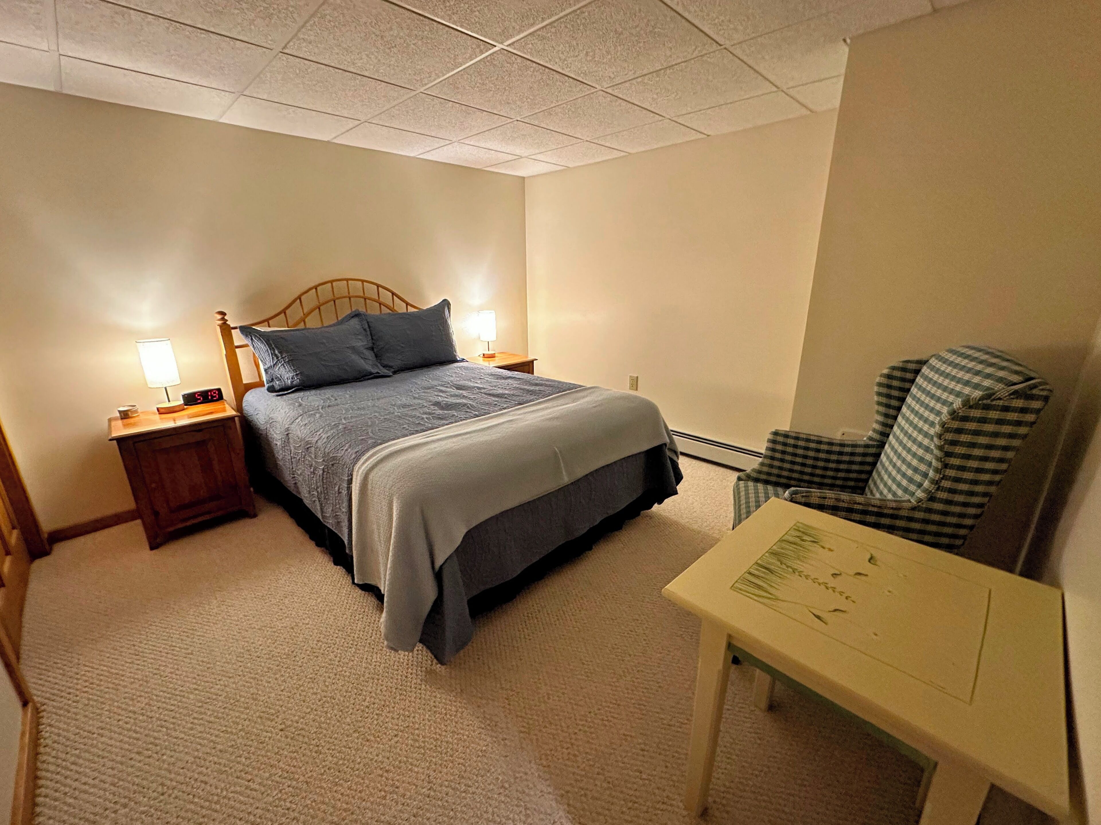 A hotel room with a bed, bedside tables, a chair, and a small table with a menu.