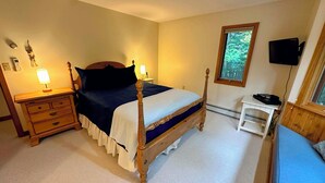 Un dormitorio con una cama con dosel, mesitas de noche, un escritorio y un televisor.