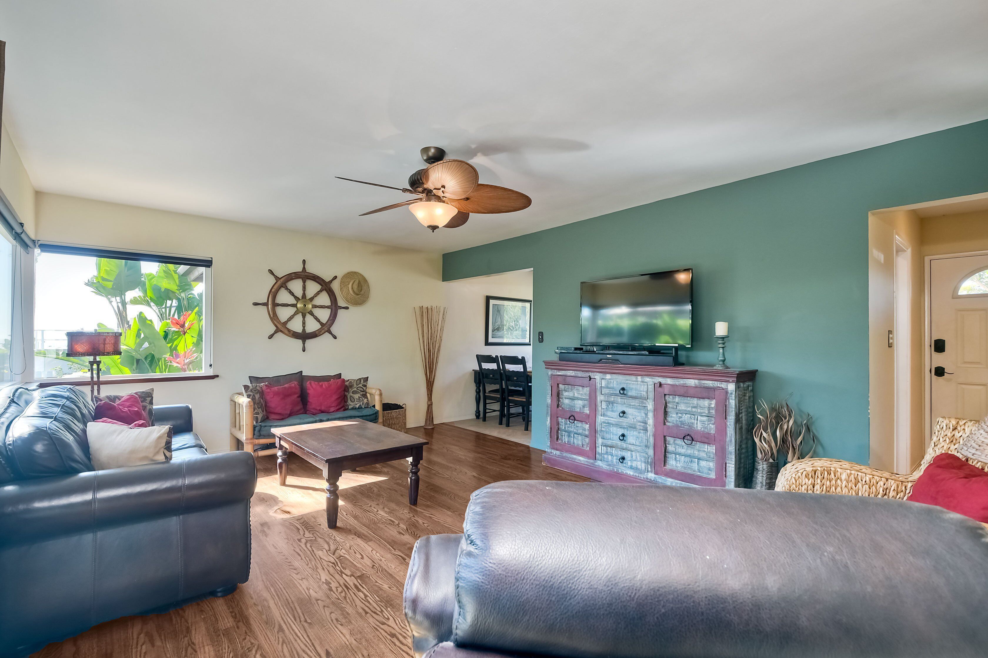 A living room with a ceiling fan, a TV, a wooden coffee table, and a dining area.
