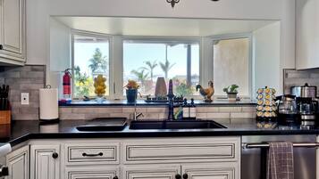A kitchen with white cabinetry, a black countertop, a large window, and decorative items.