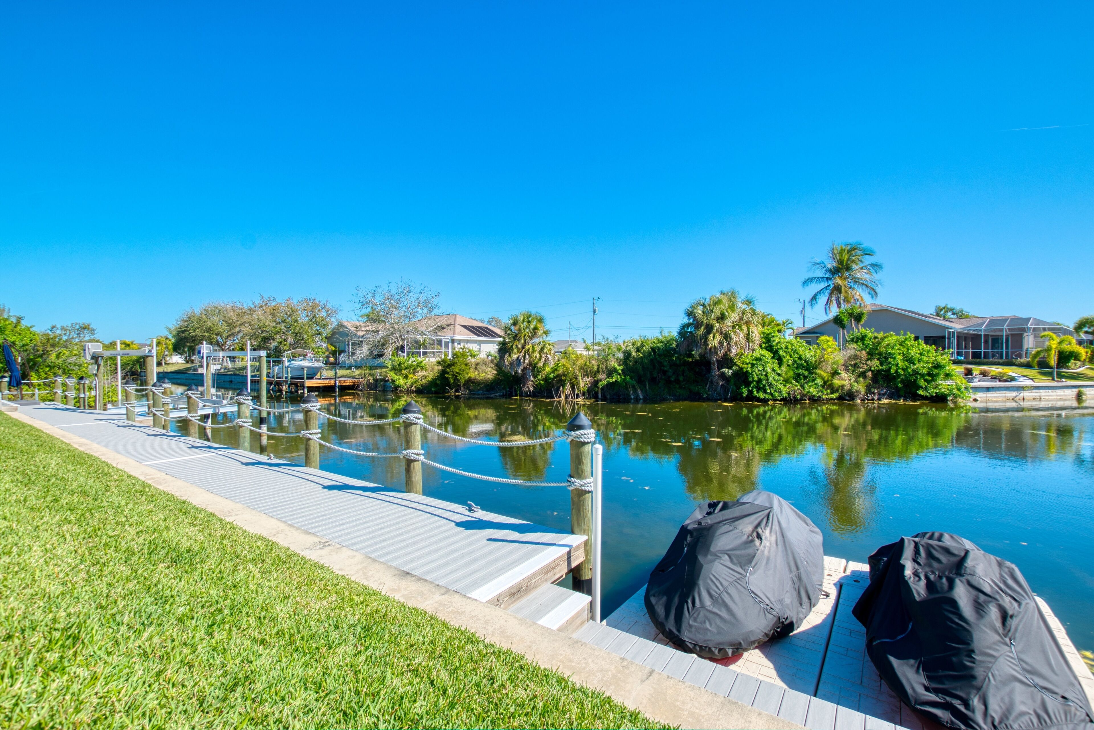 A dock with boats, a grassy area, and a calm body of water with reflections.