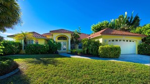 A yellow house with a red roof, a garage, and a well-maintained lawn. - Villa Viscaya (Cape Coral)