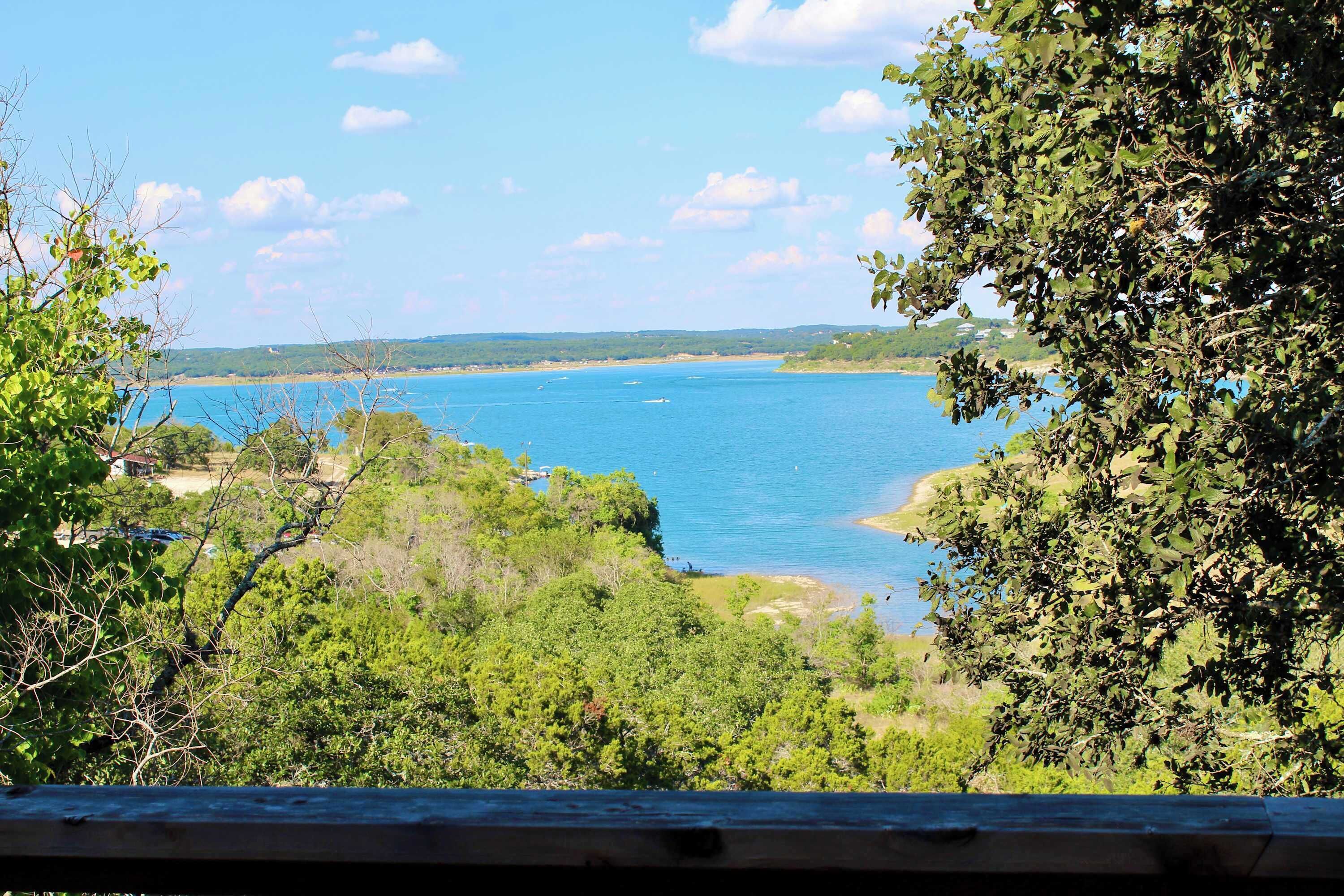 A coastal view with a clear sky, a sandy beach, and dense greenery.