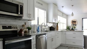 A modern kitchen with white cabinets, stainless steel appliances, and a black countertop. - Shore Nuff, a Relaxing 4-bedroom Vacation Home on Canyon Lake (Canyon Lake)