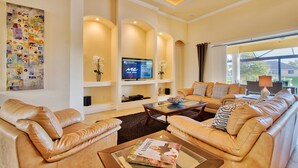 A spacious living room with a large sofa set, a flat-screen TV, and a bookshelf. - Villa Sunset View (Cape Coral)