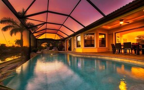 Ein Hallenbad mit Glasdecke, umgeben von einer Terrasse mit Stühlen und Tisch.
