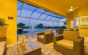 A covered outdoor seating area with wicker furniture and a view of a swimming pool. - Villa Little Diamond (Cape Coral)