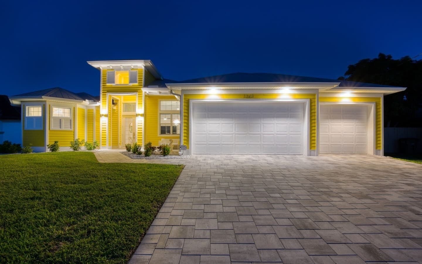 A modern two-story house with a well-maintained lawn and a paved driveway leading to a garage.