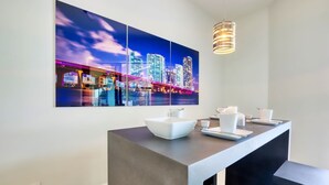 Ein modernes Hotelzimmer mit einem großen Stadtbild an der Wand, einem eleganten Konsolentisch mit weißen Schalen und Tassen sowie einer hängenden Pendelleuchte.